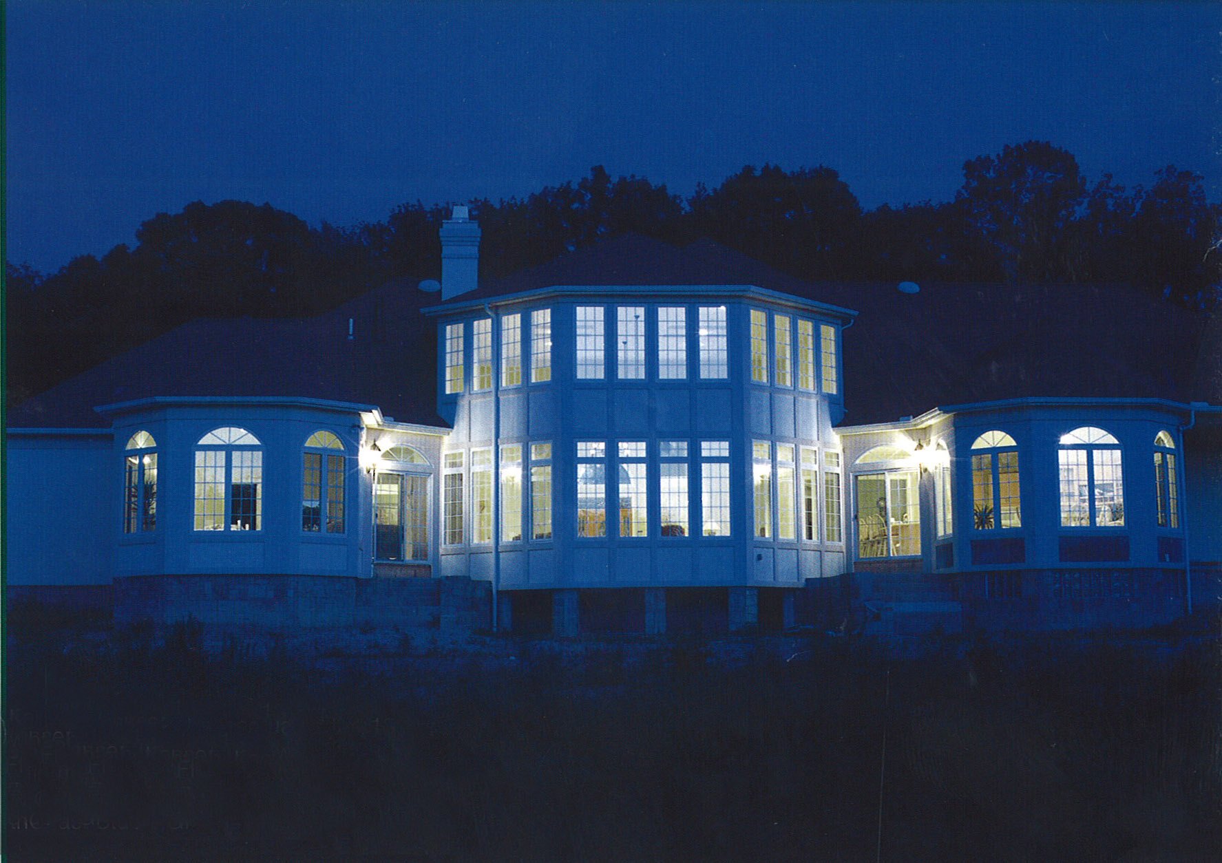 A 7,800 square foot custom home in Los Angeles at dusk, the lights on and the drive lit