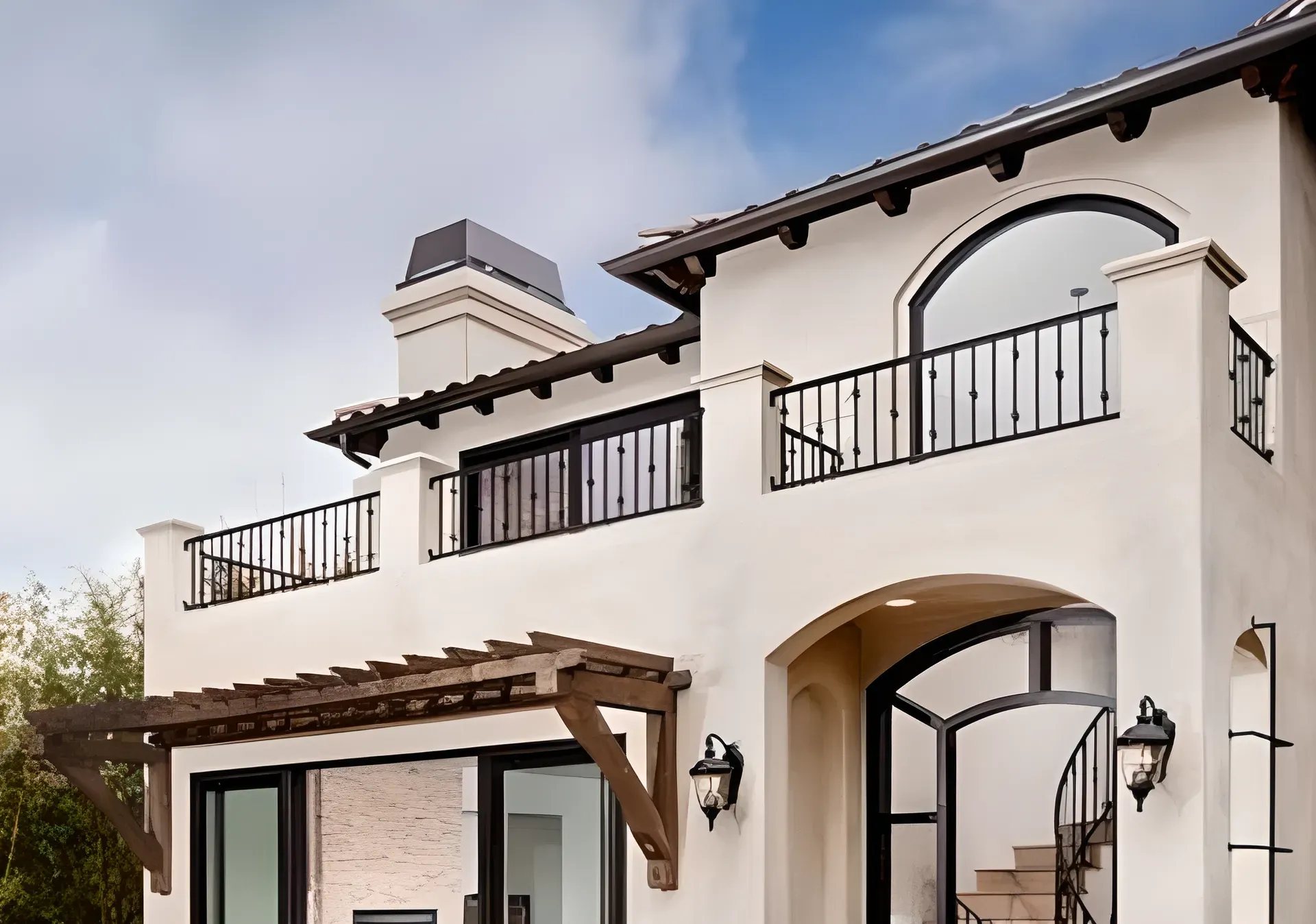 A Mediterranean-style custom home in Los Angeles, arched openings and a tiled roof, lit at dusk
